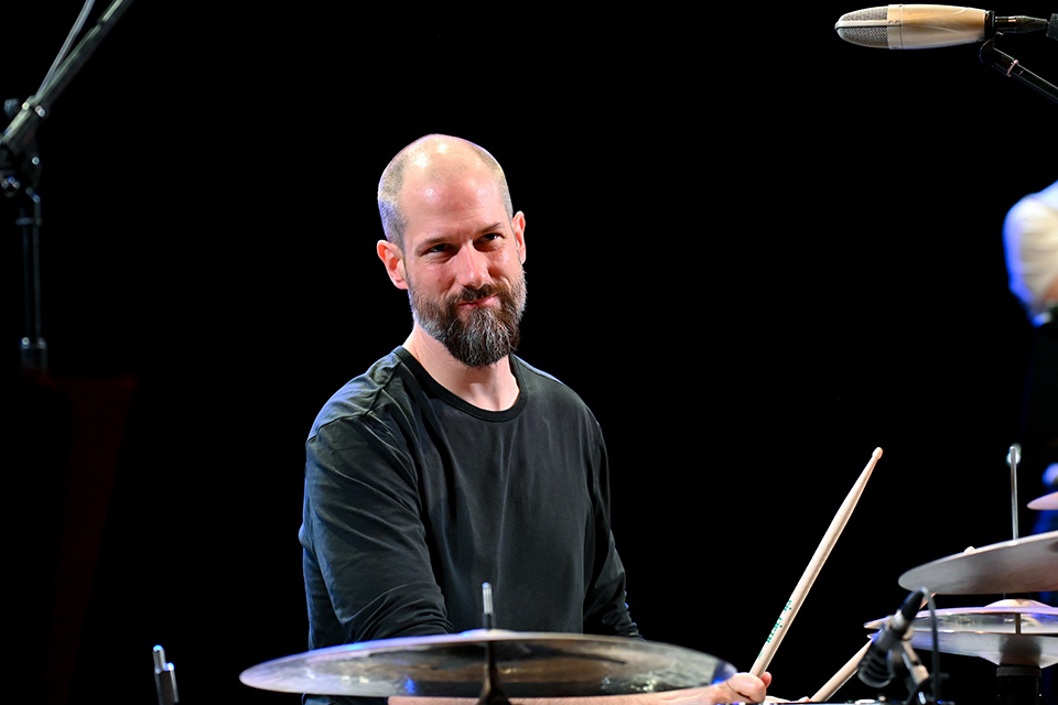 Benny Greb, a man, playing the drum kit and smiling at the audience